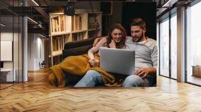 couple sitting on sofa and using laptop computer Wall mural