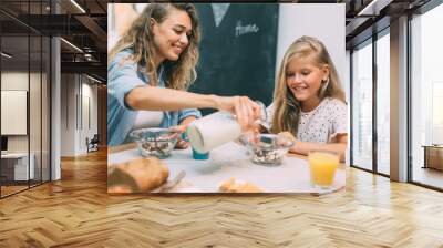 cute blonde girl having breakfast with her mother at home Wall mural