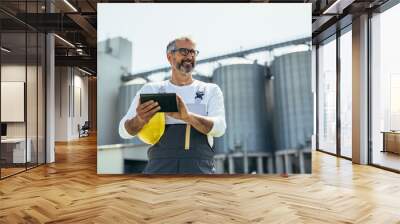 engineer using tablet in front of blurred grain silos Wall mural