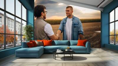 Farmer is having a handshake in the field with his partner. Wall mural