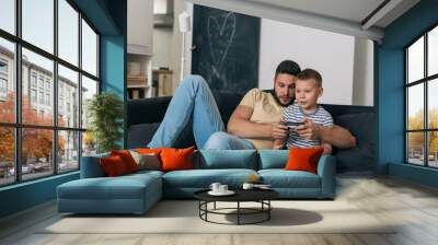 father and son playing video games on console at home Wall mural