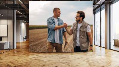 Front view of two men shaking hands in the field. Wall mural