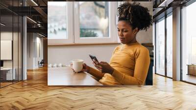 Mixed race adult woman drinks coffee at home Wall mural