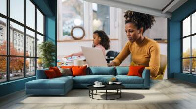 Mom is working from home with her daughter sitting next to her Wall mural