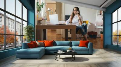 she is always on line. .young woman working on a computer in her home office Wall mural