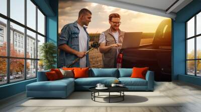 Two Caucasian men working together in the field on sunset. Wall mural