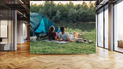 young couple enjoying camping outdoor by the river Wall mural