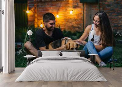 young couple playing with dog in home backyard Wall mural