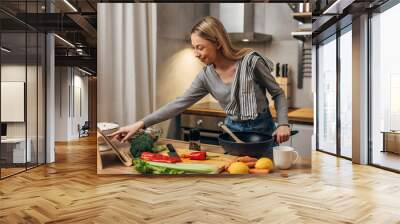 Young woman is cooking in the kitchen Wall mural