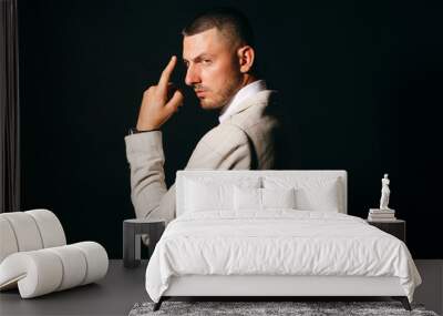 Dramatic portrait of business man in profile with hand near his face on black background. Wall mural