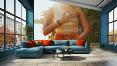 A calm woman in the lotus pose sits on a dock and practices yoga breathing near the river. Wall mural