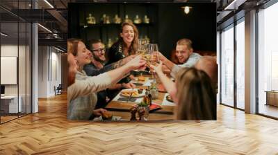 Best friends sitting in restaurant for dinner and making a toast with white wine. On table is food. Wall mural