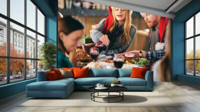 Friends having dinner at home at Christmas eve. Winter holidays concept. Wall mural