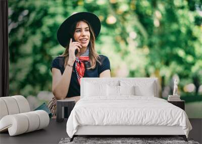 Portrait of woman using smart phone and standing in  the park after shopping. Wall mural