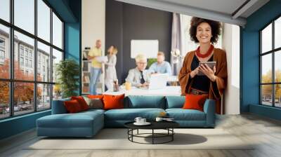 Portrait of young mixed race businesswoman. In background team working in modern office Wall mural