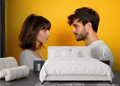 Two focused individuals share a serene moment, gazing at each other against a vibrant yellow backdrop. Wall mural