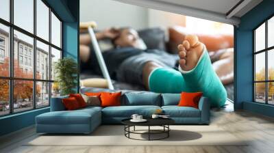 Bone fracture foot and leg on male patient with splint cast and crutches during surgery rehabilitation and orthopaedic recovery staying at home Wall mural