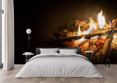 bonfire, log fire, or campfire in dark background with flame, burned log wood, firewood in home fire Wall mural