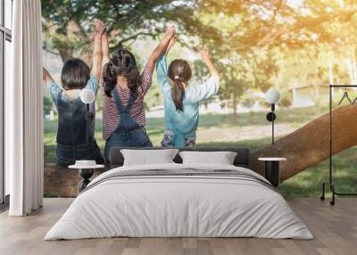 Children friendship concept with happy girl kids in the park having fun sitting under the tree shade playing together enjoying good memory and moment of student friends in old school time day Wall mural