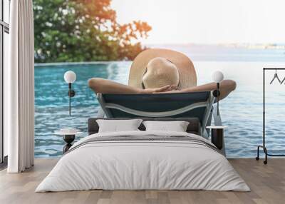 Holiday relaxation vacation of woman take it easy, happy life quality, resting on beach chair at swimming pool poolside beachfront resort hotel with summer sea sky ocean view background Wall mural