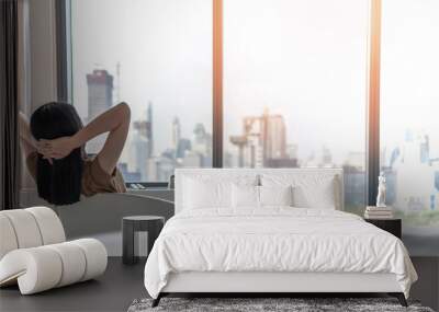 Life quality concept with young woman relaxing and resting in comfortbusiness hotel guest room or luxury home living room looking toward beautiful city view of cityscape Wall mural