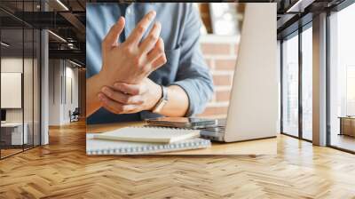 close up employee man massage on his hand and arm for relief pain from hard working on the desktop table at hoe office for stiff or cramp symptom or carpal tunnel syndrome concept Wall mural