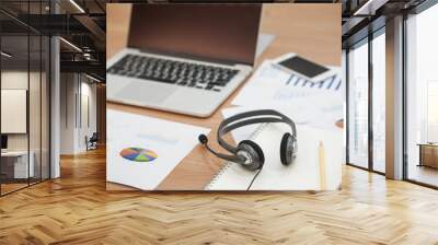 close up of headset of call centre hotline at office desk with laptop and document paper,multitasking concept Wall mural