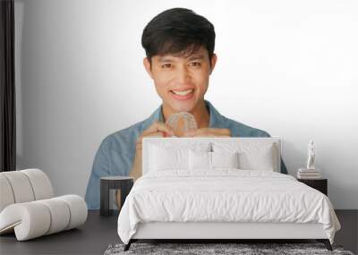 close up young asian man smiling with hand holding dental aligner retainer (invisible) isolated on white background of dental clinic for beautiful teeth treatment course concept Wall mural