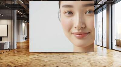 Close-up photo of an Asian woman on a white background, showing only her face and head, with her hair tied back and a slight smile on her face, for use in projects about clean skin without any problem Wall mural