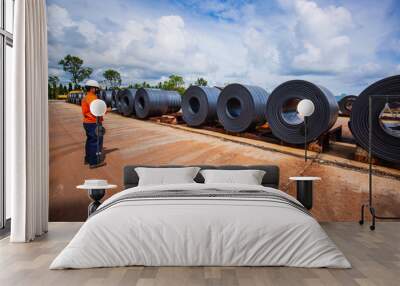 Engineer one worker man inspection on rolls of metal carbon steel sheets outside the factory Wall mural