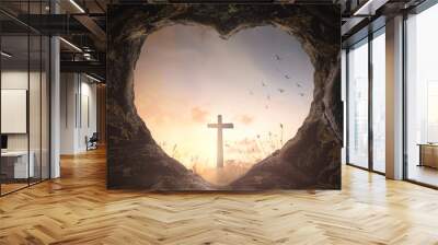 Easter Religious concept: Heart shape of empty tomb stone with the cross over meadow sunrise background Wall mural