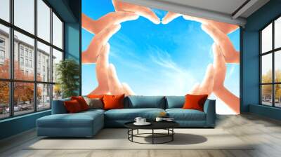 International human rights day concept: People hands in shape of heart on blue sky background Wall mural