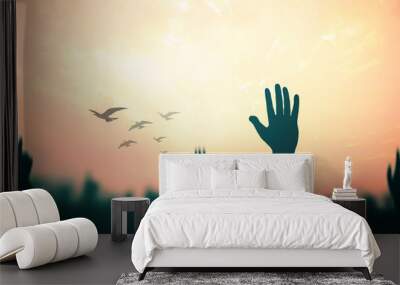 International migrants day concept: Silhouette many people raised hands with birds flying over autumn sunset background Wall mural