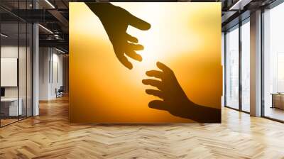 Silhouette of helping hand for support each other over sunset background Wall mural