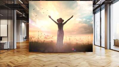 Worship concept: Silhouette of healthy woman raised hands for praise and worship God at autumn sunset meadow background Wall mural