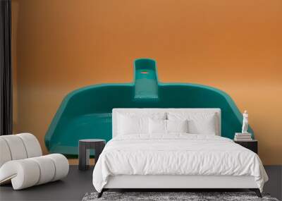 Green small dustpan To clean in the house With an orange backdrop Wall mural