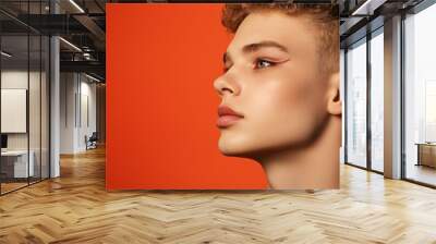 Bold and Beautiful: A striking portrait of a young woman with a modern, edgy haircut,  against a vibrant orange and green backdrop.  Her confident gaze and bold eyeliner create a captivating image. Wall mural