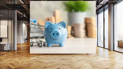 Saving for a Big Purchase: A blue piggy bank with a cheerful face sits on a table, a miniature shopping cart alongside it, suggesting a plan to save for a significant purchase. Wall mural