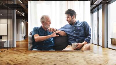 An adult hipster son and senior father living at home, talking together Wall mural