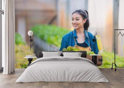 Basket with fresh vegetables, Asian farmer woman holding wooden box full of raw vegetables in the local farm or green house of Thailand, organic food by harvest in agriculture business concept Wall mural