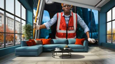 Black people worker in helmet on site construction, Excavator bulldozer male worker, Construction driver with excavator on the background, Construction worker with tractor at ground building site Wall mural