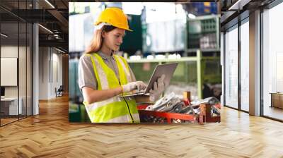 Female engineer using laptop computer for safety control checks or manufacturing maintenance work in factory building or construction site. woman engineer inspector working in industry product line Wall mural