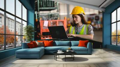 Female engineer using laptop computer for safety control checks or manufacturing maintenance work in factory building or construction site. woman engineer inspector working in industry product line Wall mural