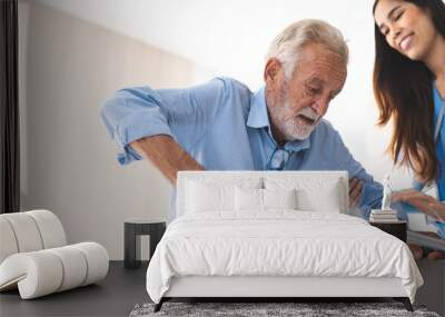 Portrait of Asian young nurse helping old elderly disable man grandfather to walk by using walker equipment in the bedroom. Senior patient of nursing home moving with walking frame and nurse support Wall mural