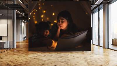 young Asian mother read the story in the book for her daughter children on the bed at home, family and motherhood learning concept Wall mural