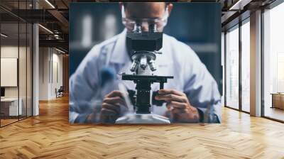 Young scientist looking through a microscope in a laboratory. Young scientist doing some research. Wall mural