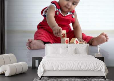 African baby girl in red cloth sitting on floor playing with wooden blocks, wooden blocks with 2024 Number, happy new year Wall mural