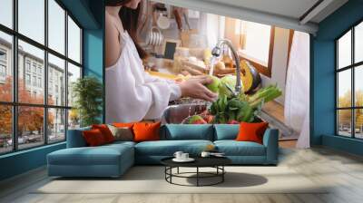 Woman's hands washing green apple to remove pesticides before cooking in kitchen under the tap Wall mural