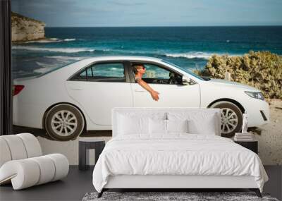 Young handsome man in a white car parked on the Australian ocean coast  Wall mural