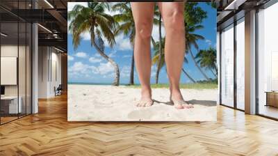 young woman standing on her legs tanning on paradise beach with palm trees Wall mural